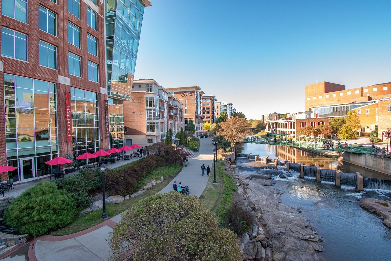 view of buildings surrounding a river with a pedestrian bridge crossing over