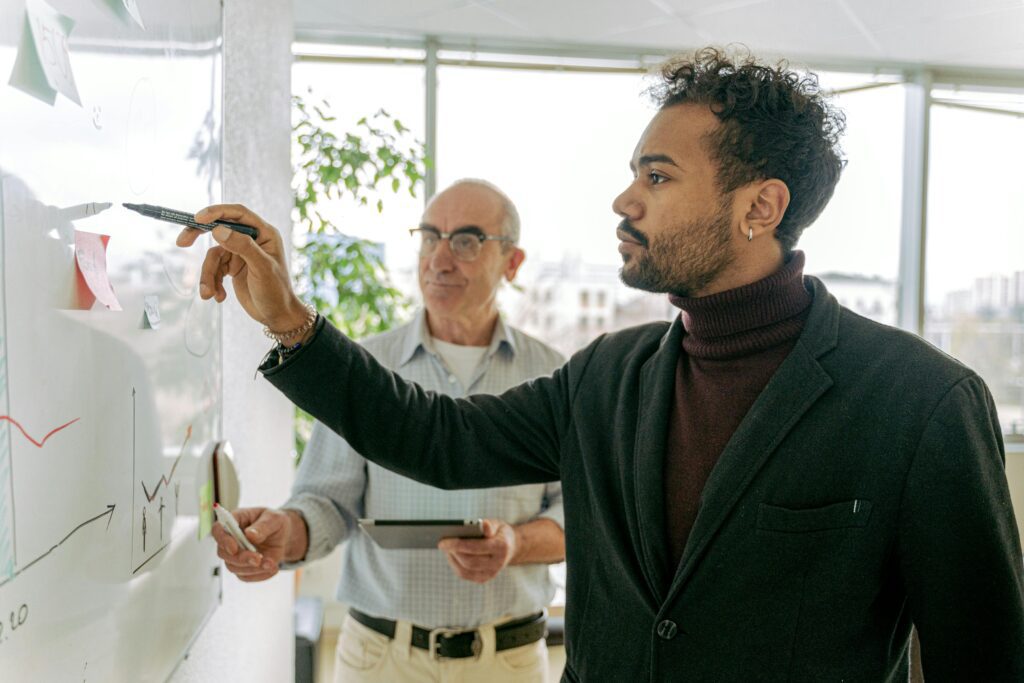 Young and senior professionals collaborating at a whiteboard in a bright office