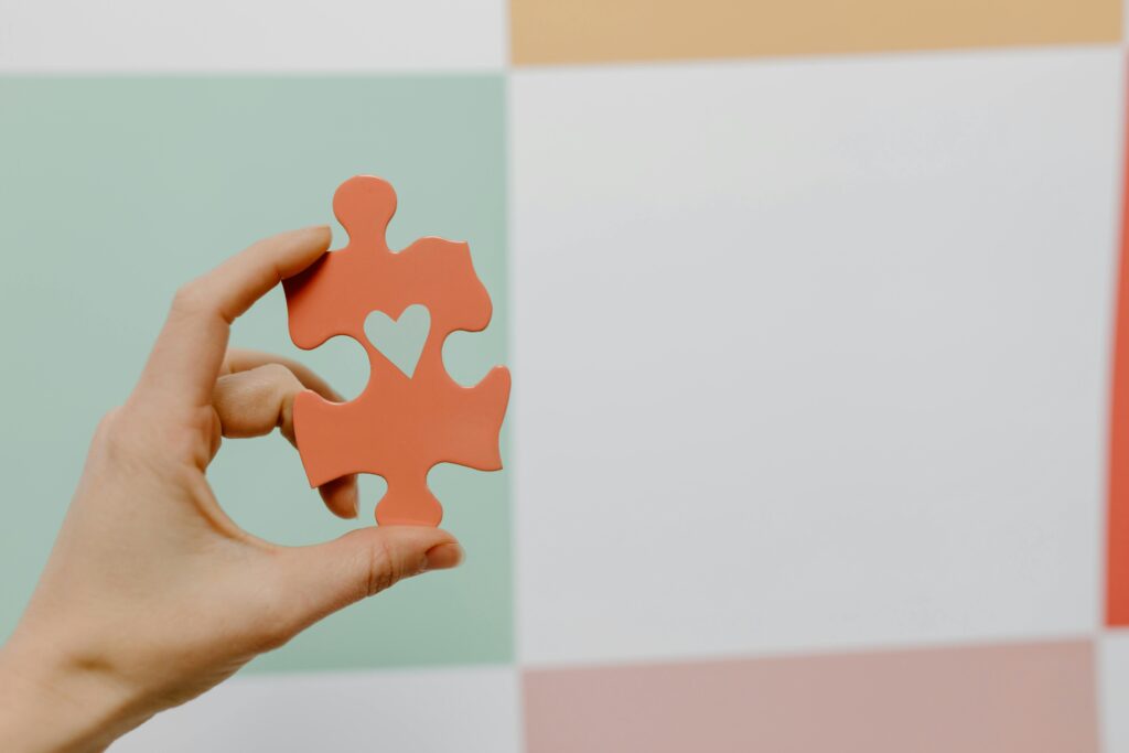Person holding a puzzle piece with a heart shape cut out of it symbolizing care, love, and charity 
