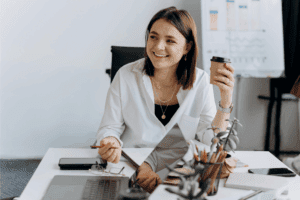 Woman smiling at her desk holding a coffee