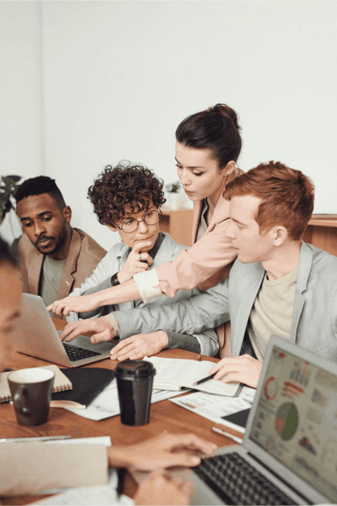 Business team collaborating in a modern office, analyzing data and brainstorming strategy on laptops – teamwork, leadership, and productivity